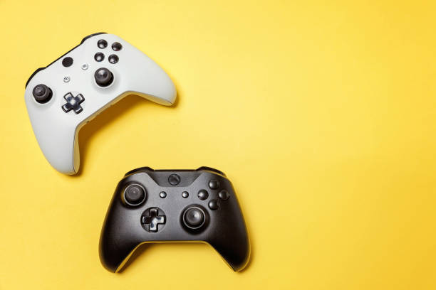 istock White and black two joystick on yellow background. Computer gaming competition videogame control confrontation concept 1149693114