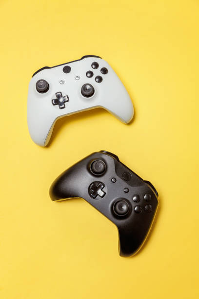 istock White and black two joystick on yellow background. Computer gaming competition videogame control confrontation concept 1149693125