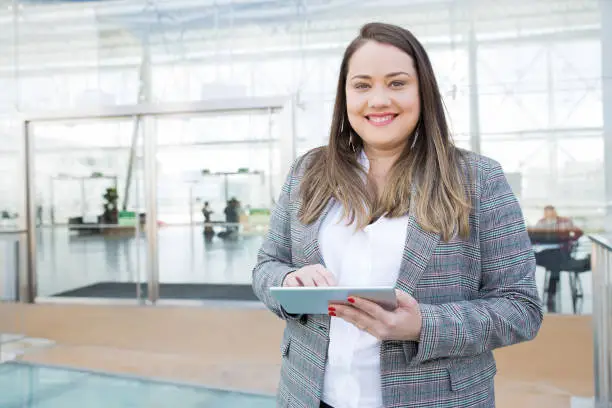 Photo of Positive lady with tablet posing in business center