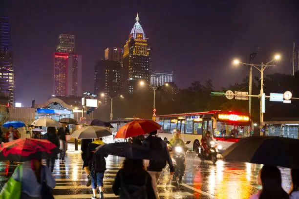 City view of Taipei downtown and rain, with people crossing the street at night