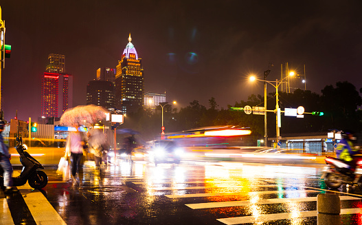 City view of Taipei with rain and abstract people crossing the street at night