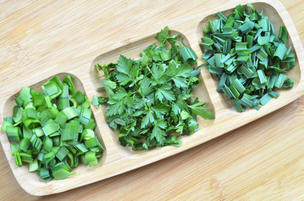 Finely chopped different greens on the kitchen Board, in a wooden plate. Top view