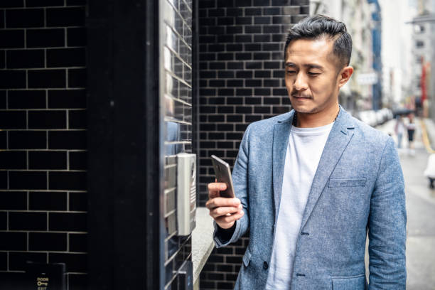 Chinese man entering his home with his smartphone