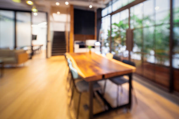 blur bokeh abstract background empty copy space .Wooden table brown tree leaf green and chair with pillow in cafe company office meeting conference customer investment marketing financial insurance