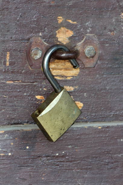 istock Unlocked padlock left open on rusted metal hinge mounted with two strong screws on dilapidated wooden boards 1149713955