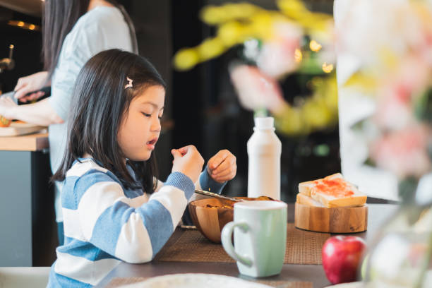 istock Asian girl kid having breakfast cereal at home kitchen 1149716374