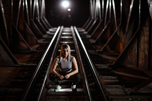 Young woman exercising on railway at night