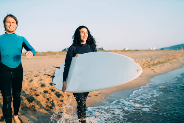 istock Happy surfers walking on sand and holding surfboards 1149725051