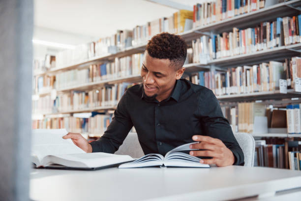 istock Smiling during the process. African american man sitting in the library and searching for some information in the books 1149725749