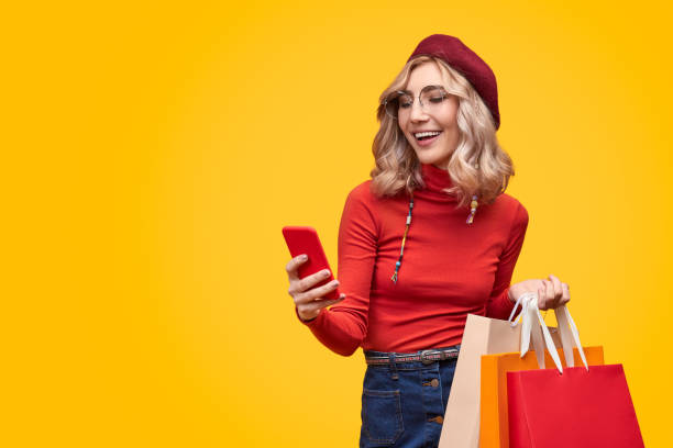 Cheerful lady with paper bags using smartphone