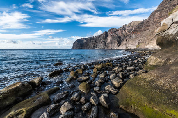 Ocean coastline with rocky cliffs and water foreground, boat, Tenerife.