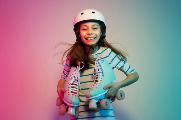 Young child girl in safety helmet with roller skates - sports Happy smiling young caucasian child girl in safety helmet holding pastel roller skates - hobby, sports and active lifestyle concept. Colorful background, layout with free text (copy) space. roller skating stock pictures, royalty-free photos & images