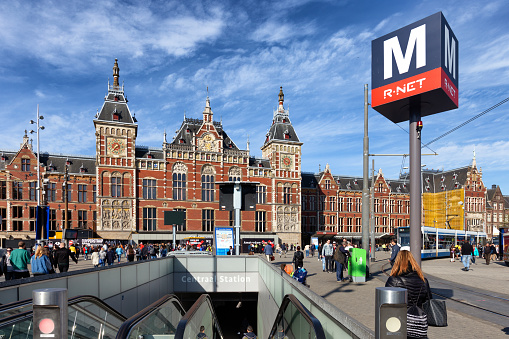Amsterdam, Netherlands - May 15, 2019: Crowds around the entrance to Amsterdam's centraal Station. This rail, tram, metro, bus and boat network hub is one of Europe's largest and busiest public transport network stations.