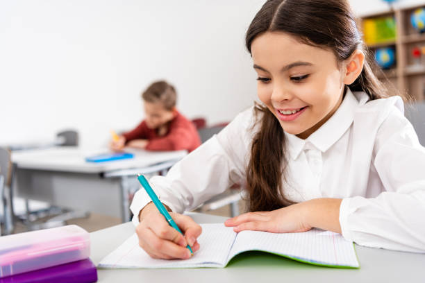 istock Smiling schoolgirl writing in notebook during lesson in classroom 1149728991