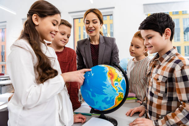istock Teacher and pupils looking at globe while studying geography in classroom 1149729021