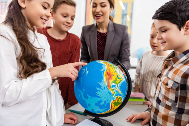 istock Teacher and pupils looking at globe while studying geography in classroom 1149729040