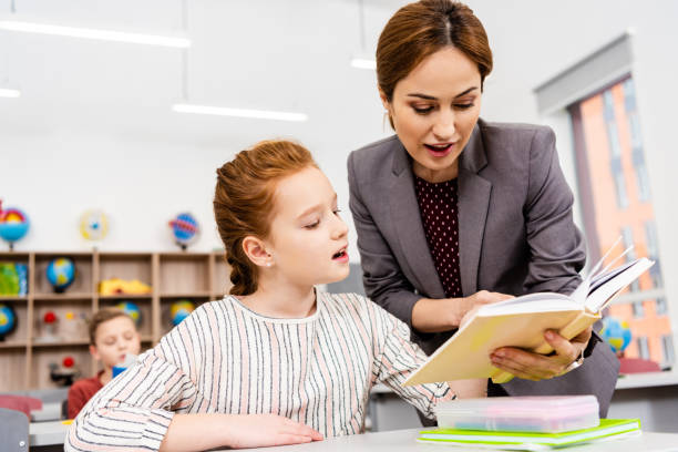 istock Teacher standing near desk and explaining lesson to pupil in classroom 1149729047