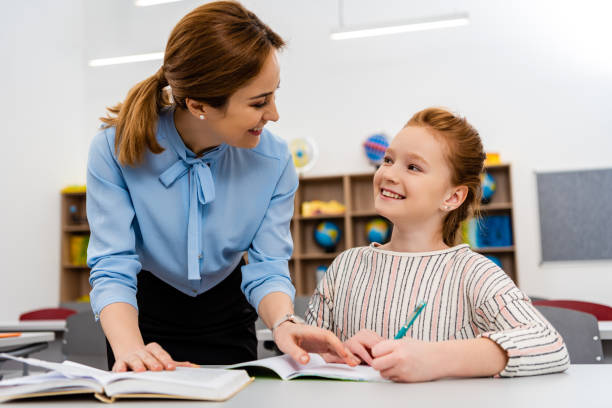 istock Teacher in blue blouse explaining lesson to pupil in classroom 1149729141