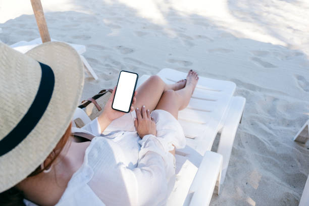 istock a woman holding white mobile phone with blank desktop screen while laying down on beach chair 1149734088