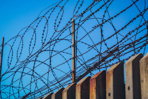 istock Barbed wire on top of a concrete wall. 1149738875