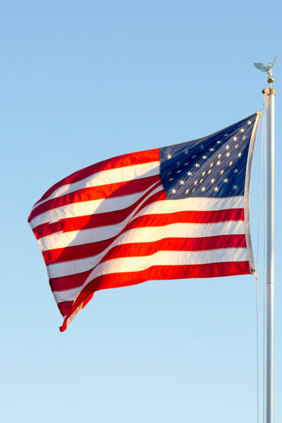 istock American National Flag Flitting in the Wind on Blue Sky BAckground 1149742433