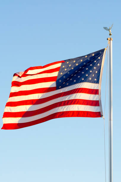 istock American National Flag Flitting in the Wind on Blue Sky BAckground 1149742485
