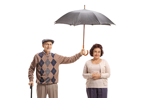 Elderly gentleman holding an umbrella over an elderly lady isolated on white background