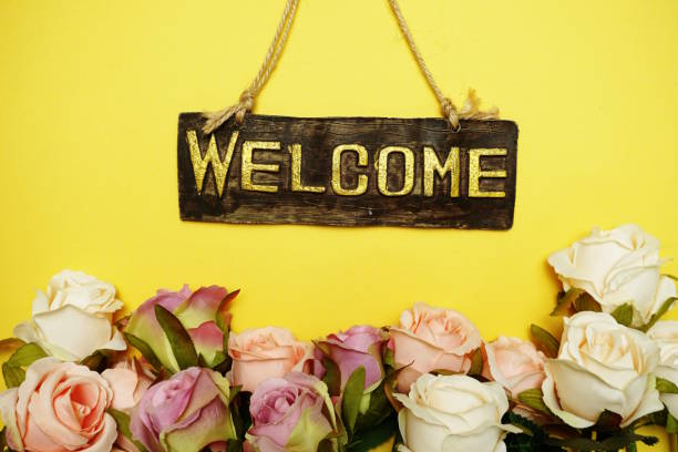 istock welcome sign with rose flower on yellow background 1149746161