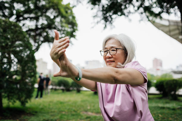 Taiwanese Lady Staying Fit With Tai Chi At The Park A senior Taiwanese lady staying fit and healthy with some Tai Chi at the park. taiwan people stock pictures, royalty-free photos & images