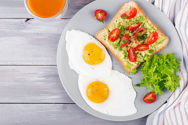 istock Breakfast. Fried egg, vegetable salad and a grilled avocado sandwich on a grey background. Top view 1149750975