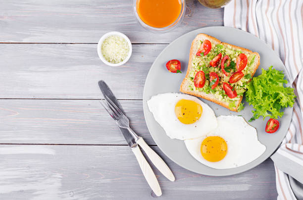 istock Breakfast. Fried egg, vegetable salad and a grilled avocado sandwich on a grey background. Top view 1149750984