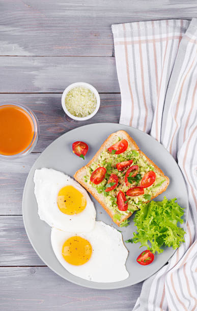 istock Breakfast. Fried egg, vegetable salad and a grilled avocado sandwich on a grey background. Top view 1149751002