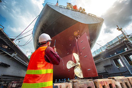 A male port worker looking into the distance with cranes in the background