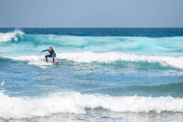 woman surfing on waves in tenerife, playa de las americas, spain - playa de las américas imagens e fotografias de stock