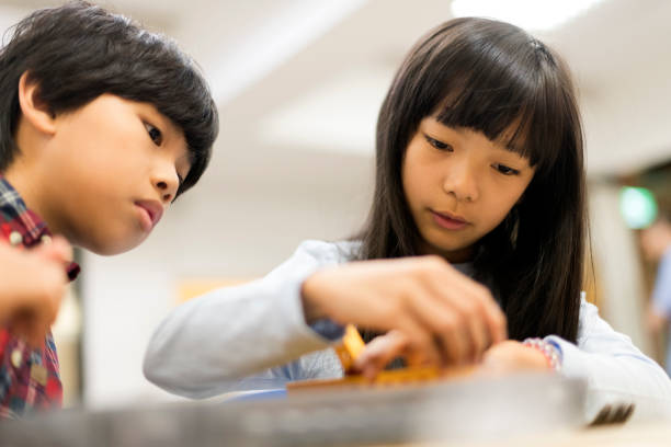 istock Young boy watches as his fellow student assembles robotic parts 1149753988