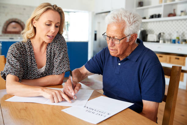 Woman Helping Senior Man To Complete Last Will And Testament At Home Woman Helping Senior Man To Complete Last Will And Testament At Home will legal document photos stock pictures, royalty-free photos & images