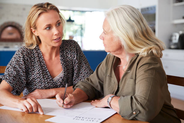 Female Friend Helping Senior Woman To Complete Last Will And Testament At Home Female Friend Helping Senior Woman To Complete Last Will And Testament At Home will legal document photos stock pictures, royalty-free photos & images