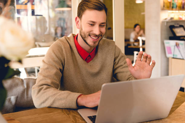 istock happy blogger waving hand while having video chat on laptop in cafe 1149759736