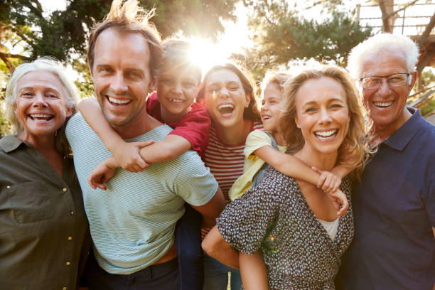 ritratto all'aperto di famiglia multi-generazione che cammina in campagna contro il sole svolagliante - gruppo medio di persone foto e immagini stock