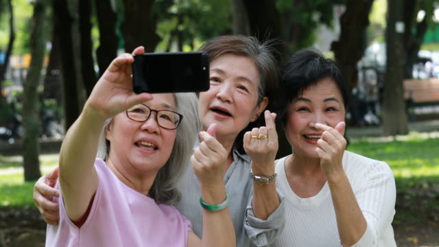 Three Senior Taiwanese Ladies Taking Selfies In The Park