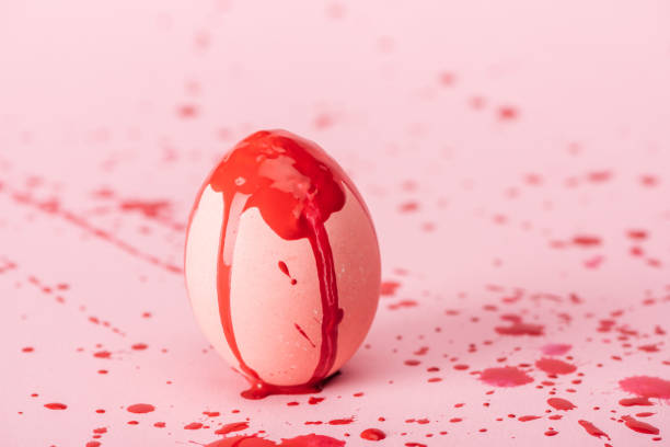 easter egg with red paint spills on pink with copy space