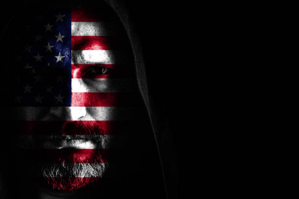 istock Brutal man with a gray beard in the hood with sharp shadows on a black background. Copy space. 1149763310