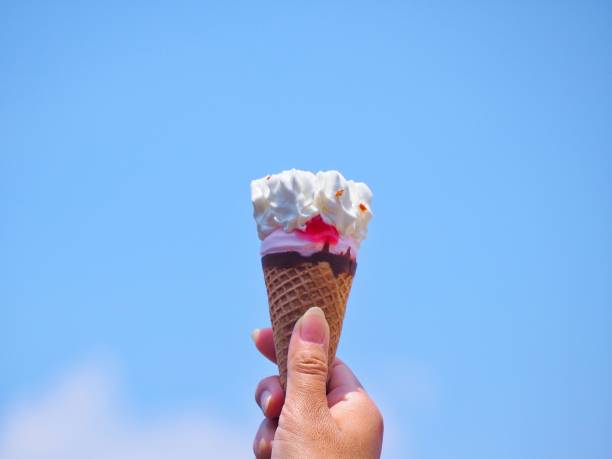 istock female hand holding ice cream cone with blue sky background in summer day - image 1149764515