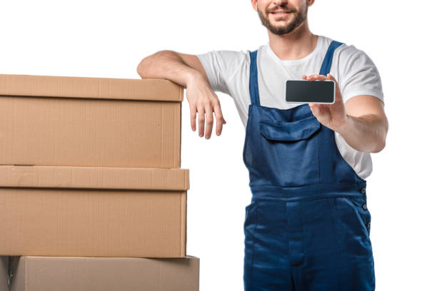 istock partial view of smiling mover with cardboard boxes presenting smartphone with blank screen isolated on white 1149766582
