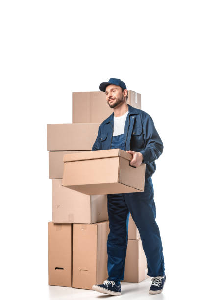 istock handsome mover in uniform carrying cardboard box isolated on white 1149766666
