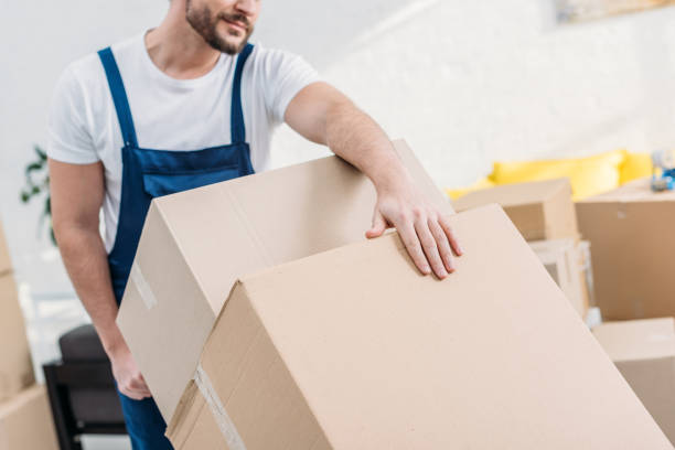 istock cropped view of mover in uniform transporting cardboard boxes in apartment 1149768894
