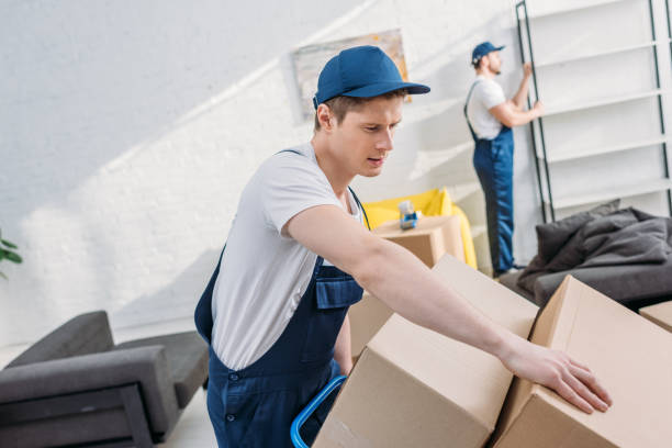 istock two movers transporting cardboard boxes and furniture in apartment with copy space 1149768902
