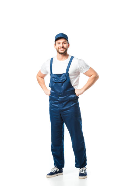 istock handsome smiling mover in uniform with hands akimbo looking at camera isolated on white 1149768942