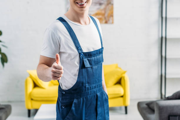 cropped view of mover in uniform showing thumb up sign in apartment