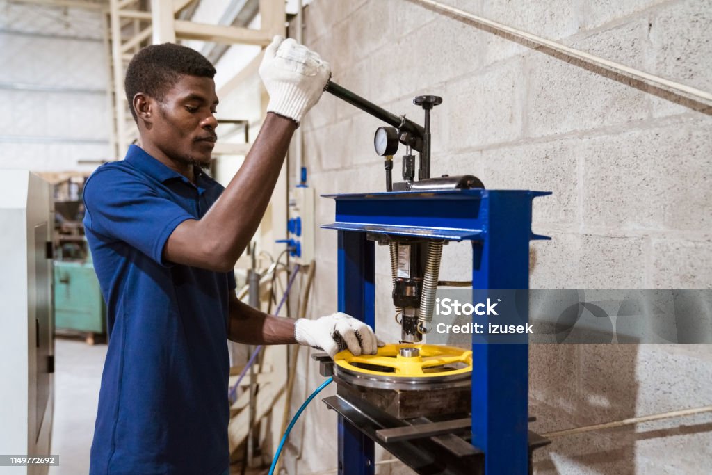 Male engineer working on wheel with lathe machine Young engineer working on wheel with lathe machine. Male apprentice is wearing uniform. He is in manufacturing industry. Engineer Stock Photo